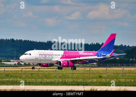 Memmingerberg, Bavière, Allemagne - 28 juin 2025 : un Airbus A320 exploité par les taxis Wizz Air est installé sur la piste de l'aéroport FMM de Memmingen. L'avion porte la superbe livrée rose et bleue de la compagnie aérienne ou low cost *** Ein Airbus A320 der Fluggesellschaft Wizz Air Rollt auf dem Rollfeld des Flughafens Memmingen FMM zur Startbahn. Der Jet trägt die auffällige rose-blaue Lackierung der Airline bzw Billigfluggesellschaft Banque D'Images
