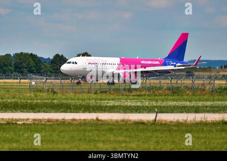 Memmingerberg, Bavière, Allemagne - 28 juin 2025 : un Airbus A320 exploité par les taxis Wizz Air est installé sur la piste de l'aéroport FMM de Memmingen. L'avion porte la superbe livrée rose et bleue de la compagnie aérienne ou low cost *** Ein Airbus A320 der Fluggesellschaft Wizz Air Rollt auf dem Rollfeld des Flughafens Memmingen FMM zur Startbahn. Der Jet trägt die auffällige rose-blaue Lackierung der Airline bzw Billigfluggesellschaft Banque D'Images