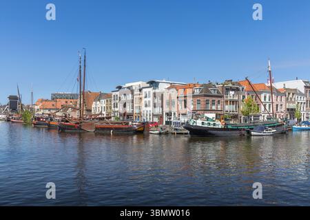 Un canal serein à Leyde, aux pays-Bas, bordé de maisons hollandaises historiques et de bateaux traditionnels sous un ciel bleu clair, incarnant le charmant wa européen Banque D'Images