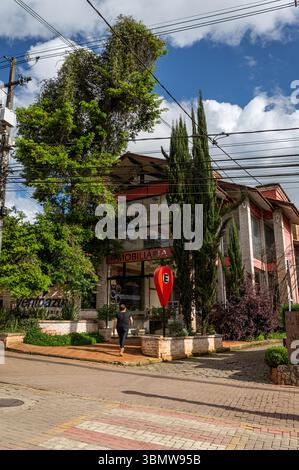 Femme marche vers l'agence immobilière Ventoazul à l'avenue pavée Monte Verde, flanquée de grands cyprès sous ciel nuageux. Banque D'Images