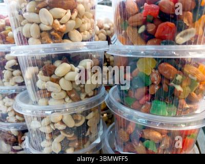 Divers types de noix et de fruits secs sont soigneusement disposés dans des récipients en plastique transparent exposés sur un marché local, invitant les clients à profiter d'un HEA Banque D'Images