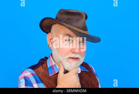 Chapeau de cow-boy en cuir. Portrait d'homme barbu en chapeau de cow-boy. Des cowboys en chapeau. Beau macho barbu. Cow-boy américain. Homme barbu en chemise à carreaux Banque D'Images