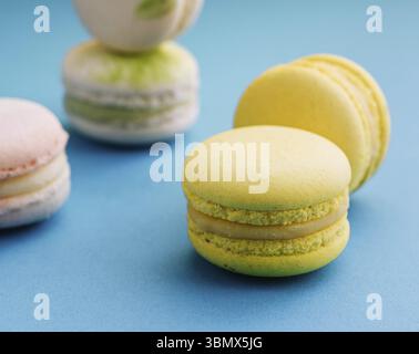 Nourriture nature morte, macarons doux et colorés sur bleu avec fond jaune Banque D'Images