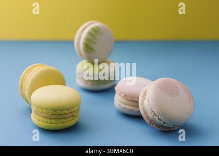 Nourriture nature morte, macarons doux et colorés sur bleu avec fond jaune Banque D'Images