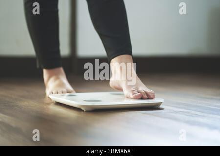 Pieds de femme debout sur une balance numérique pour le contrôle de l'alimentation Banque D'Images