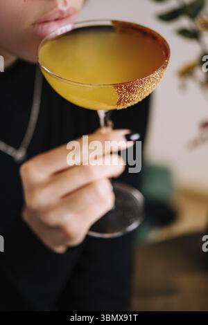 Nature morte, fille buvant un cocktail de bananes jaunes dans un verre à martini Banque D'Images