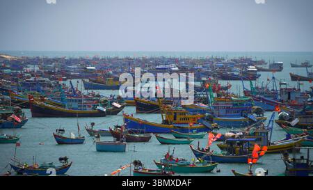 Port de pêche bondé avec des bateaux vietnamiens traditionnels colorés dans la mer à Mui ne, Vietnam Banque D'Images