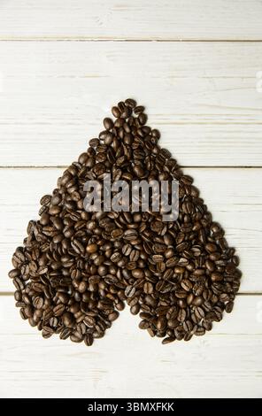 Les grains de café en forme de cœur se forment sur fond de planche en bois peint blanc dans un design plat Banque D'Images