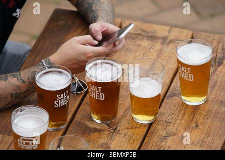 Plusieurs verres de bière sur une table en bois dans un cadre extérieur. Brighton, Angleterre Banque D'Images
