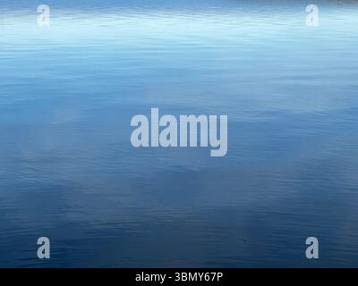 L'océan tranquille s'étend vers l'horizon, reflétant le ciel bleu et les nuages doux au-dessus. Banque D'Images