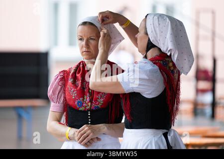 Crostwitz, Allemagne. 29 juin 2025. Deux membres d'un groupe de danse se préparent pour le défilé du 15e Festival international de folklore de Lusatia. Au total, dix ensembles du monde entier seront invités au festival de musique et de danse en haute et basse Lusace bilingue du 26 au 29 juin 2025. Crédit : Sebastian Kahnert/dpa/Alamy Live News Banque D'Images