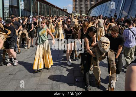 Londres, Royaume-Uni. 29 juin 2025. Les troupeaux traversent le pont animé de Westfield, où marionnettes animales, danseurs et spectateurs se mélangent. LES TROUPEAUX géantes font face à une intervention de danse des danseurs de Sadler's Wells qui tentent d'arrêter les TROUPEAUX alors qu'ils voyagent de Westfield Stratford à Sadler's Wells East où ils jouent dans une finale. LES TROUPEAUX sont l'art public et action climatique. D’avril à août 2025, des animaux marionnettes grandeur nature parcourent un itinéraire de 20 000 km entre le bassin du Congo et le cercle arctique, symbolisant leur fuite après un désastre climatique avec des arrêts dans de nombreuses villes et pays, à Londres en juillet Banque D'Images