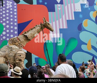 Londres, Royaume-Uni. 29 juin 2025. Les troupeaux trottent le long des boutiques et se mêlent aux spectateurs curieux. LES marionnettes d'animaux géants des TROUPEAUX rencontrent une intervention de danse des danseurs de Sadler's Wells qui tentent d'arrêter LES TROUPEAUX alors qu'ils voyagent de Westfield Stratford à Sadler's Wells East où ils jouent dans une finale. LES TROUPEAUX sont l'art public et l'action climatique. D’avril à août 2025, les animaux marionnettes grandeur nature parcourent un itinéraire de 20 000 km entre le bassin du Congo et le cercle arctique, symbolisant leur fuite de la catastrophe climatique avec des arrêts dans de nombreuses villes et pays, à Londres du 27 au 29 juillet. Banque D'Images