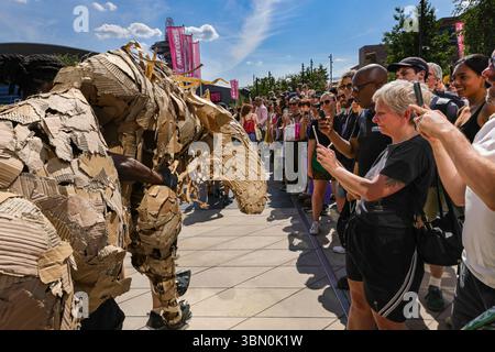 Londres, Royaume-Uni. 29 juin 2025. Les troupeaux trottent le long des boutiques et se mêlent aux spectateurs curieux, un animal interagit avec les gens qui prennent des photos. LES marionnettes d'animaux géants des TROUPEAUX rencontrent une intervention de danse des danseurs de Sadler's Wells qui tentent d'arrêter LES TROUPEAUX alors qu'ils voyagent de Westfield Stratford à Sadler's Wells East où ils jouent dans une finale. LES TROUPEAUX sont l'art public et l'action climatique. D’avril à août 2025, les animaux marionnettes grandeur nature parcourent un itinéraire de 20 000 km entre le bassin du Congo et le cercle arctique, symbolisant leur fuite des catastrophes climatiques avec des arrêts dans de nombreuses villes et pays, Banque D'Images