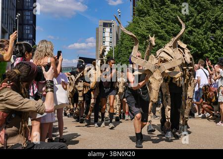 Londres, Royaume-Uni. 29 juin 2025. Les troupeaux trottent le long des boutiques et se mêlent aux spectateurs curieux. LES marionnettes d'animaux géants des TROUPEAUX rencontrent une intervention de danse des danseurs de Sadler's Wells qui tentent d'arrêter LES TROUPEAUX alors qu'ils voyagent de Westfield Stratford à Sadler's Wells East où ils jouent dans une finale. LES TROUPEAUX sont l'art public et l'action climatique. D’avril à août 2025, les animaux marionnettes grandeur nature parcourent un itinéraire de 20 000 km entre le bassin du Congo et le cercle arctique, symbolisant leur fuite de la catastrophe climatique avec des arrêts dans de nombreuses villes et pays, à Londres du 27 au 29 juillet. Banque D'Images
