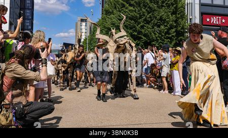 Londres, Royaume-Uni. 29 juin 2025. Les troupeaux trottent le long des boutiques et se mêlent aux spectateurs curieux. LES marionnettes d'animaux géants des TROUPEAUX rencontrent une intervention de danse des danseurs de Sadler's Wells qui tentent d'arrêter LES TROUPEAUX alors qu'ils voyagent de Westfield Stratford à Sadler's Wells East où ils jouent dans une finale. LES TROUPEAUX sont l'art public et l'action climatique. D’avril à août 2025, les animaux marionnettes grandeur nature parcourent un itinéraire de 20 000 km entre le bassin du Congo et le cercle arctique, symbolisant leur fuite de la catastrophe climatique avec des arrêts dans de nombreuses villes et pays, à Londres du 27 au 29 juillet. Banque D'Images