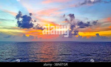 Un coucher de soleil éclatant sur la mer des Caraïbes présente un spectre saisissant de couleurs, des bleus et violets profonds aux oranges et jaunes vifs Banque D'Images