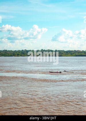 Deux personnes pêchant dans des bateaux en bois sur le fleuve Amazone, entouré par la jungle tropicale luxuriante d'Amazonas, Colombie. Banque D'Images