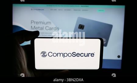 Dans cette illustration photo, une personne tient un téléphone portable avec le logo de la société américaine de carte de paiement CompoSecure Inc sur l'écran en face de la page Web. Banque D'Images