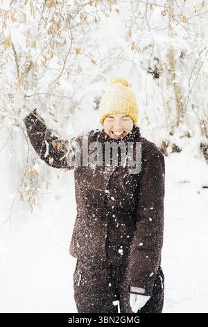Jeune femme en vêtements chauds sous la neige. Vacances d'hiver drôles de neige Banque D'Images