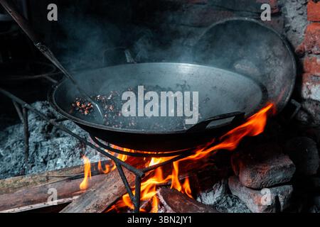 Torréfaction traditionnelle de grains de café mélangés avec du maïs sur un poêle à bois de chauffage. Une technique locale pour créer une saveur distincte, capturée dans un village rustique. Banque D'Images