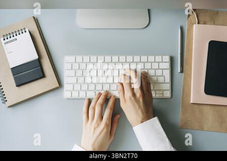 Mains féminines élégantes tapant sur un clavier d'ordinateur, vue de dessus d'un lieu de travail moderne Banque D'Images