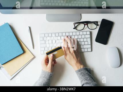 Vue de dessus sur un bureau de travail. Carte de crédit entre les mains. Commande en ligne avec livraison porte. Services bancaires en ligne et paiement de factures. Mainstream dans la vie Banque D'Images