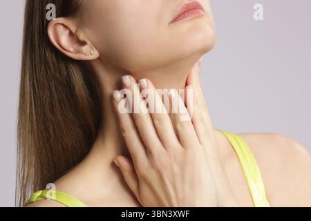Femme caucasienne touchant sa gorge. Mal de gorge, rhume, grippe, amygdalite ou problème de glande thyroïde Banque D'Images