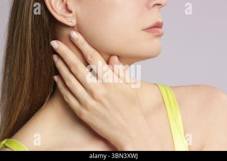 Femme caucasienne touchant sa gorge. Mal de gorge, rhume, grippe, amygdalite ou problème de glande thyroïde Banque D'Images