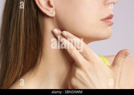 Femme caucasienne touchant sa gorge. Mal de gorge, rhume, grippe, amygdalite ou problème de glande thyroïde Banque D'Images