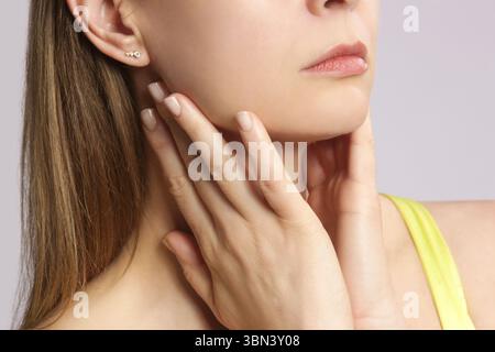 Femme caucasienne touchant sa gorge. Mal de gorge, rhume, grippe, amygdalite ou problème de glande thyroïde Banque D'Images