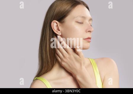 Femme caucasienne touchant sa gorge. Mal de gorge, rhume, grippe, amygdalite ou problème de glande thyroïde Banque D'Images