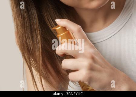 Femme appliquant de l'huile sur les extrémités des cheveux, pointes de cheveux fendus, cheveux secs ou concept de protection solaire Banque D'Images