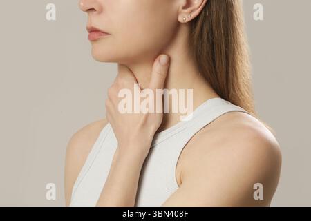 Femme caucasienne touchant sa gorge. Mal de gorge, rhume, grippe, amygdalite ou problème de glande thyroïde Banque D'Images