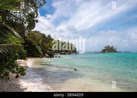 Un paysage tropical aux eaux turquoises, aux collines luxuriantes et aux rochers éparpillés s’étend le long de la côte de l’île de Mahé aux Seychelles. Banque D'Images