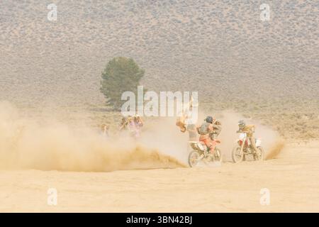 Pilote de motocross effectuant des cascades inversées dans une course dans le désert Banque D'Images