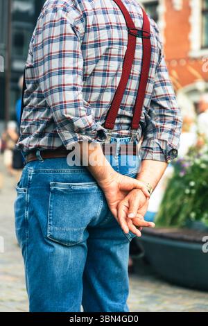 Homme, les mains dans l'eau avec chemise à carreaux et bretelles Banque D'Images