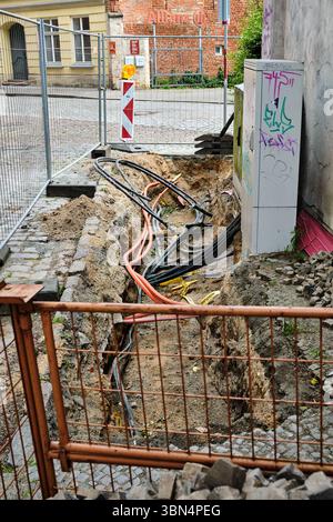 28 juin 2025 - Stralsund-Allemagne : une section de trottoir dans la vieille ville de Stralsund est ouverte pour des travaux d'alimentation souterraine, avec des câbles exposés Banque D'Images