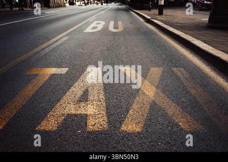 Taxi et panneaux de bus sur l'asphalte dans la ville, vue rapprochée. Banque D'Images