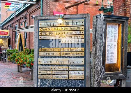 Un panneau rustique dans le Distillery District énumère les variétés d'huîtres et les brasseries artisanales utilisant des lattes en bois gravées, encadrées par un filet de pêche et un a chaud Banque D'Images