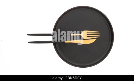 Assiette noire avec fourchette et couteau en or Banque D'Images