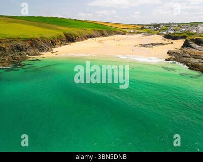 Une vue aérienne des gens profitant d'une journée ensoleillée sur une plage avec une eau turquoise claire, rivage de sable et falaises verdoyantes. Banque D'Images