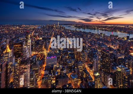 Vue aérienne de New York sur Midtown et Lower Manhattan au crépuscule, avec gratte-ciel illuminés et coucher de soleil sur l'Hudson River Banque D'Images