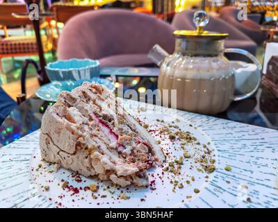 Gros plan d'un délicieux gâteau à plusieurs couches avec des pistaches et de la crème, un régal sucré parfait dans un cadre de restaurant chic. Banque D'Images