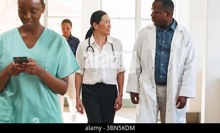 Équipe de soins de santé diversifiée communiquant dans le couloir d'un hôpital Banque D'Images
