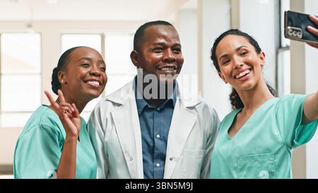Des professionnels de la santé souriant ensemble tout en prenant un Selfie de groupe dans une clinique moderne Banque D'Images