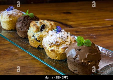 Une variété de muffins sucrés différents sur une plaque de verre allongée Banque D'Images