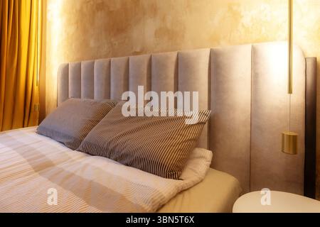Cette chambre d'hôtel moderne et confortable dispose d'un grand lit avec oreillers moelleux et tête de lit moelleuse Banque D'Images