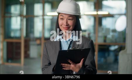 Femme asiatique constructeur architecte inspecteur approuve le plan de construction projet de construction écrivant des notes chinoise coréenne japonaise jeune ingénieur civil Banque D'Images