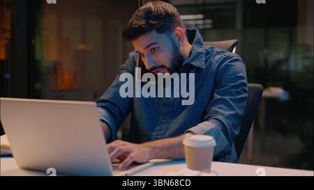 Homme d'affaires indien homme d'affaires multitâche homme d'affaires dans la nuit tard le travail d'heures supplémentaires de bureau parlant appel de téléphone mobile discuter du commerce d'ordinateur portable Banque D'Images